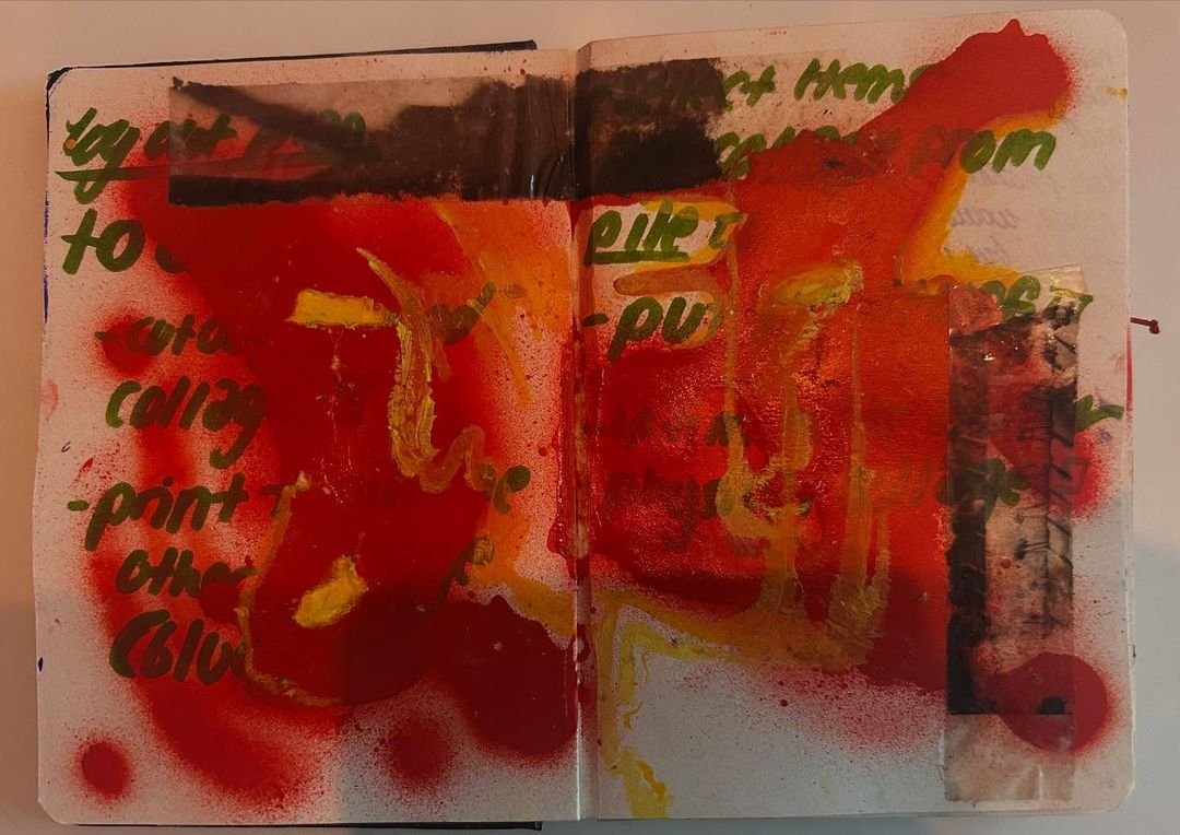 Working sketchbook page: red and orange spray over green handwritten planning notes, partly held down by strips of dark tape.